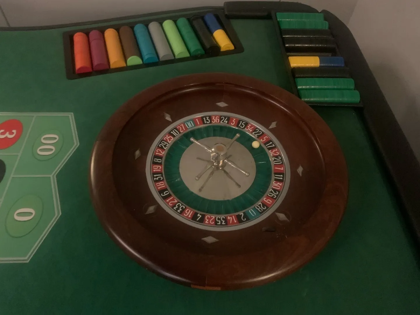 A roulette wheel and some colored chips on the table.