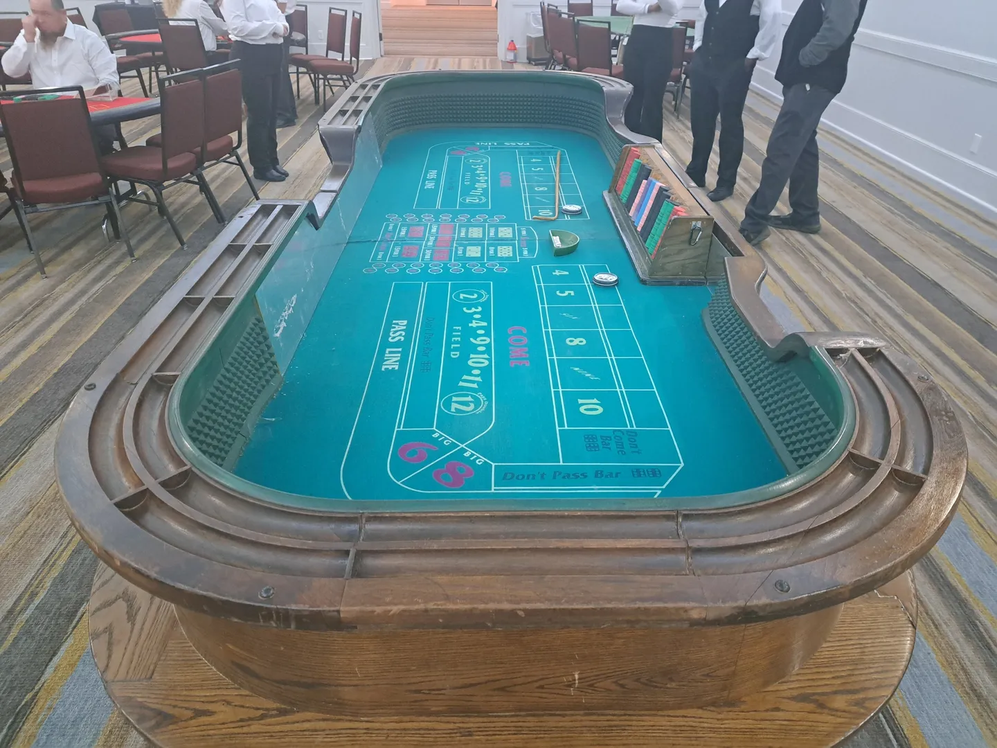 A large craps table with people standing around it.